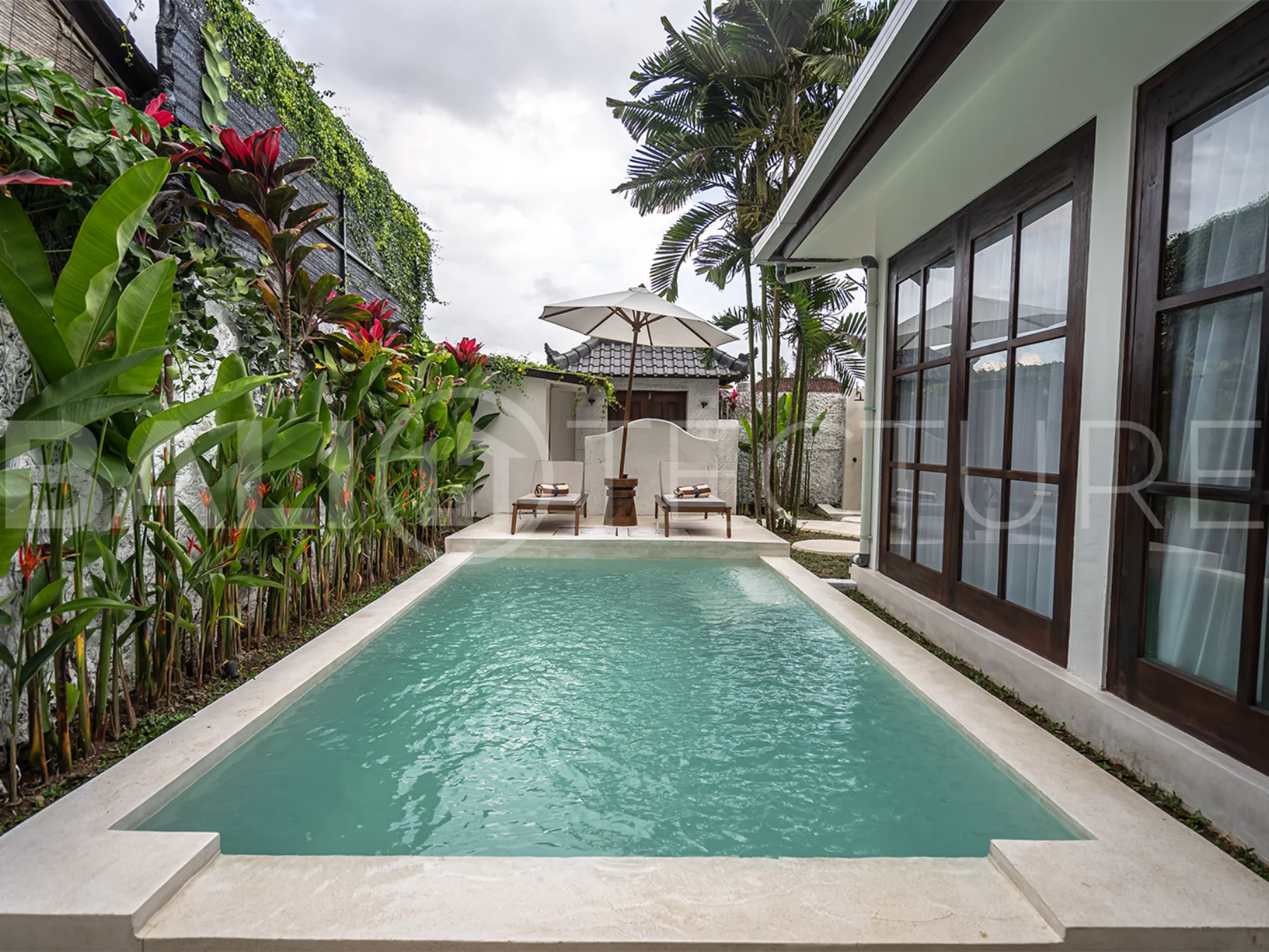 Tranquil outdoor pool area surrounded by greenery in a luxurious Bali property.