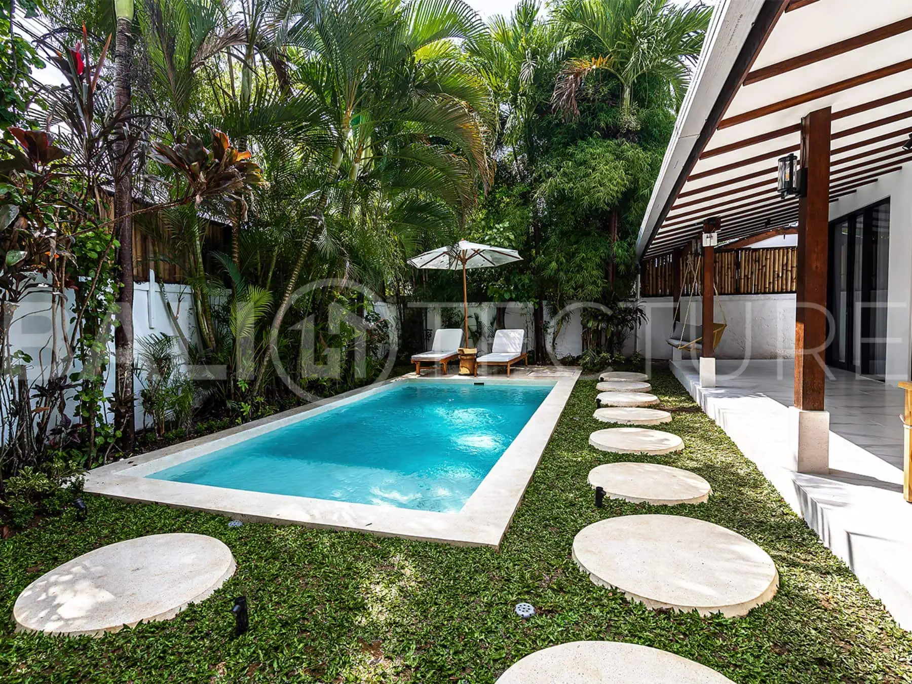 Tranquil outdoor pool area surrounded by greenery in a luxurious Bali property.