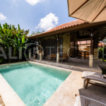 A cozy bedroom in a contemporary Ubud villa, offering comfort and views of lush tropical surroundings.