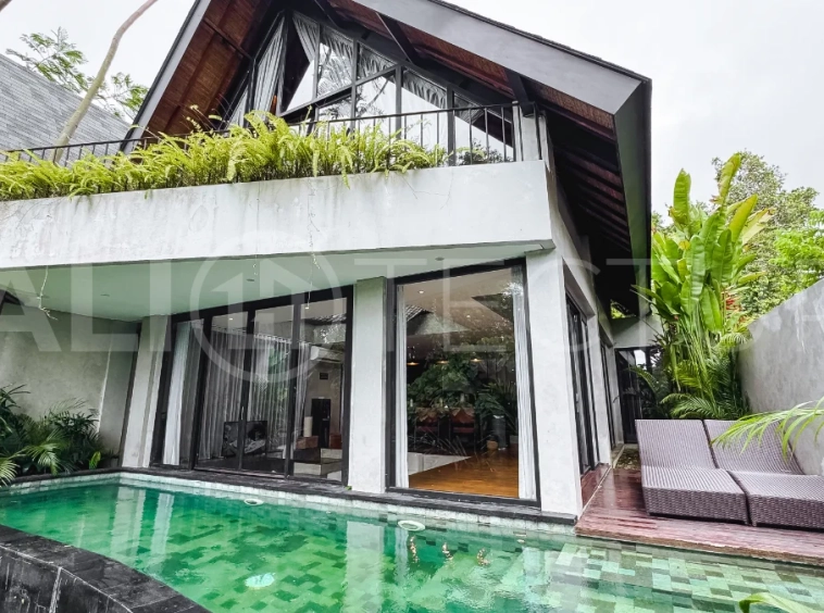 Luxury tropical-style 1-bedroom villa near Tanah Lot, Bali, featuring a two-story design with an open-plan living area, fully equipped kitchen, floor-to-ceiling glass windows, private swimming pool, river views, and lush tropical surroundings. The ensuite bedroom includes a private balcony overlooking the pool. Fully furnished and managed for rental income, this leasehold investment property is conveniently located near Tanah Lot Temple, Luna Beach Club, Nuanu City, beaches, restaurants, and cafés.