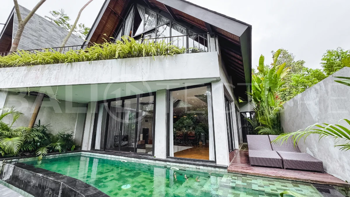 Luxury tropical-style 1-bedroom villa near Tanah Lot, Bali, featuring a two-story design with an open-plan living area, fully equipped kitchen, floor-to-ceiling glass windows, private swimming pool, river views, and lush tropical surroundings. The ensuite bedroom includes a private balcony overlooking the pool. Fully furnished and managed for rental income, this leasehold investment property is conveniently located near Tanah Lot Temple, Luna Beach Club, Nuanu City, beaches, restaurants, and cafés.