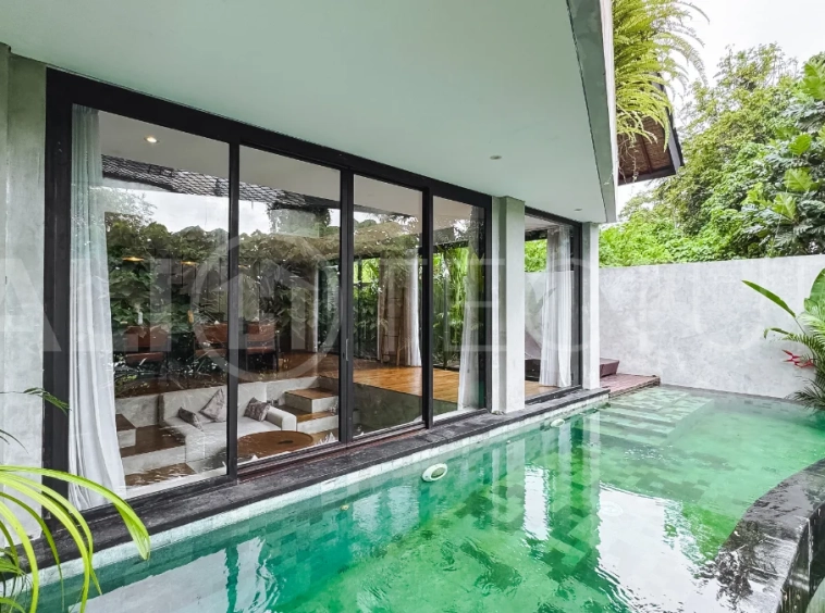 Luxury tropical-style 1-bedroom villa near Tanah Lot, Bali, featuring a two-story design with an open-plan living area, fully equipped kitchen, floor-to-ceiling glass windows, private swimming pool, river views, and lush tropical surroundings. The ensuite bedroom includes a private balcony overlooking the pool. Fully furnished and managed for rental income, this leasehold investment property is conveniently located near Tanah Lot Temple, Luna Beach Club, Nuanu City, beaches, restaurants, and cafés.