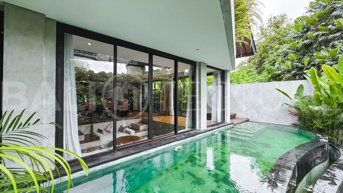 Luxury tropical-style 1-bedroom villa near Tanah Lot, Bali, featuring a two-story design with an open-plan living area, fully equipped kitchen, floor-to-ceiling glass windows, private swimming pool, river views, and lush tropical surroundings. The ensuite bedroom includes a private balcony overlooking the pool. Fully furnished and managed for rental income, this leasehold investment property is conveniently located near Tanah Lot Temple, Luna Beach Club, Nuanu City, beaches, restaurants, and cafés.