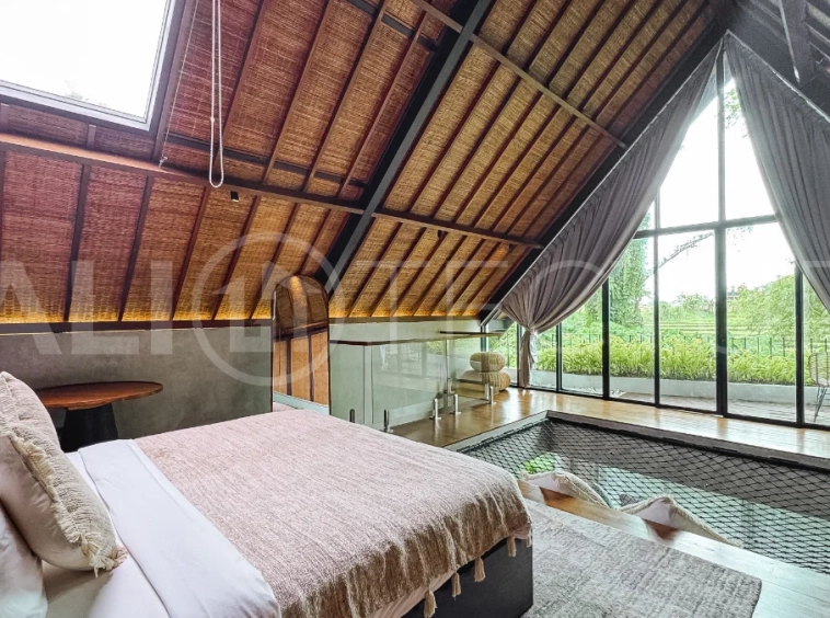 Luxury tropical-style 1-bedroom villa near Tanah Lot, Bali, featuring a two-story design with an open-plan living area, fully equipped kitchen, floor-to-ceiling glass windows, private swimming pool, river views, and lush tropical surroundings. The ensuite bedroom includes a private balcony overlooking the pool. Fully furnished and managed for rental income, this leasehold investment property is conveniently located near Tanah Lot Temple, Luna Beach Club, Nuanu City, beaches, restaurants, and cafés.