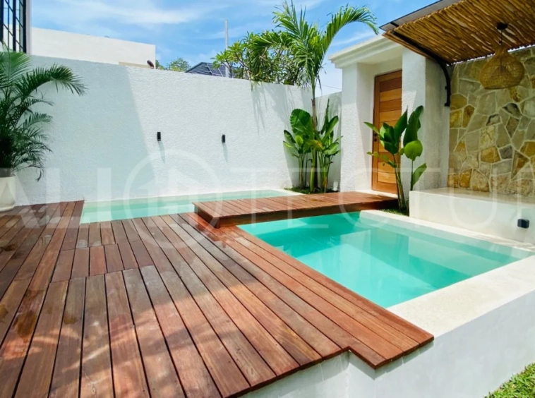 Modern 1-bedroom villa for sale in Balangan featuring a private swimming pool, tropical garden, wooden pool deck, minimalist interiors, and a peaceful residential setting near Balangan Beach.