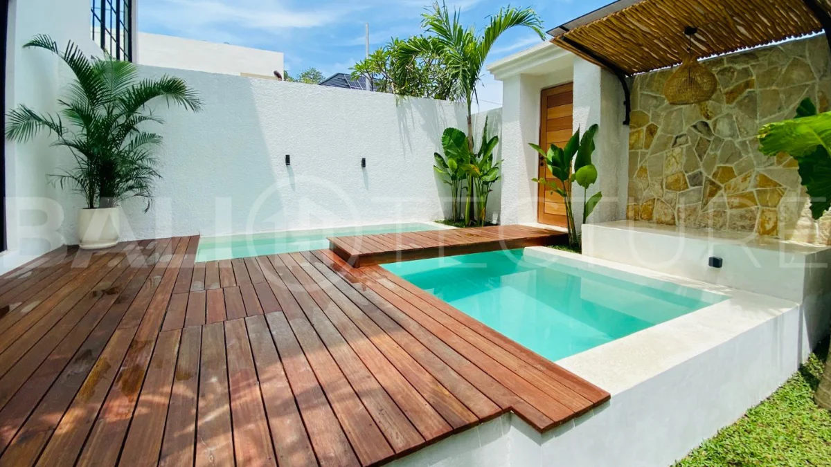 Modern 1-bedroom villa for sale in Balangan featuring a private swimming pool, tropical garden, wooden pool deck, minimalist interiors, and a peaceful residential setting near Balangan Beach.