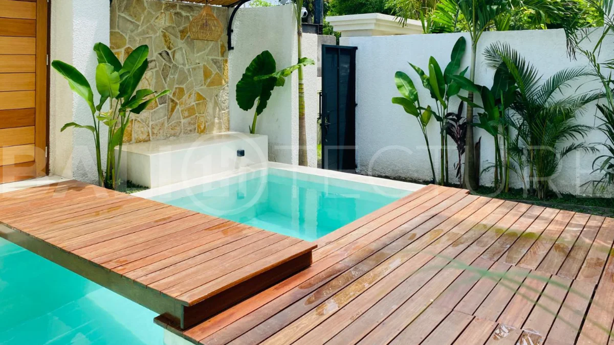 Modern 1-bedroom villa for sale in Balangan featuring a private swimming pool, tropical garden, wooden pool deck, minimalist interiors, and a peaceful residential setting near Balangan Beach.