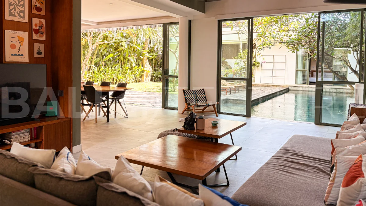 Modern four-bedroom villa in Tumbak Bayuh, Pererenan, featuring a private 12-meter swimming pool, tropical garden, double-height living area, spacious outdoor terrace, and contemporary furnished interiors on a 5.5-are plot.