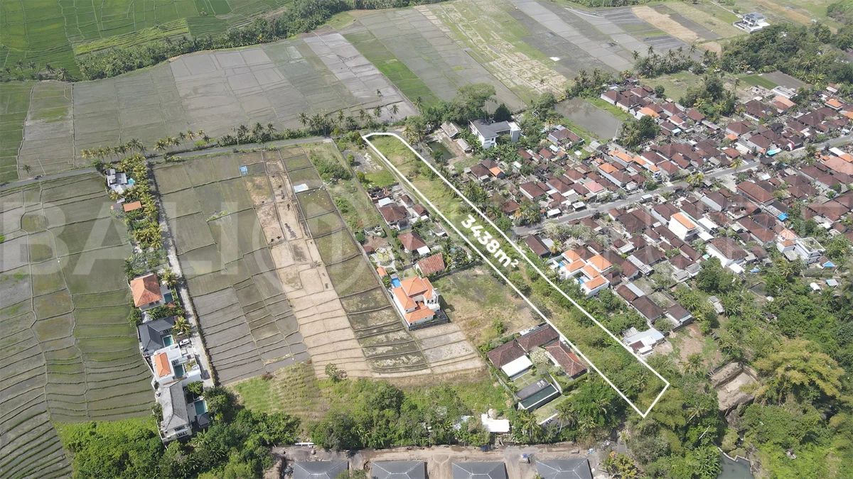 3,438 sqm east-facing riverside leasehold land in Kaba Kaba, Bali, surrounded by protected green-zone rice fields with panoramic river, rice terrace, and mountain views, featuring 4-meter asphalt road access and ideal for villa development.