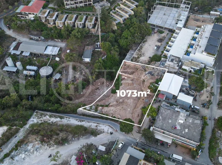 Aerial view of 1,073m² leasehold land for sale near Bingin Beach, Uluwatu, overlooking the ocean with stunning sunset views, surrounded by villas, cafés, restaurants, and coastal developments.
