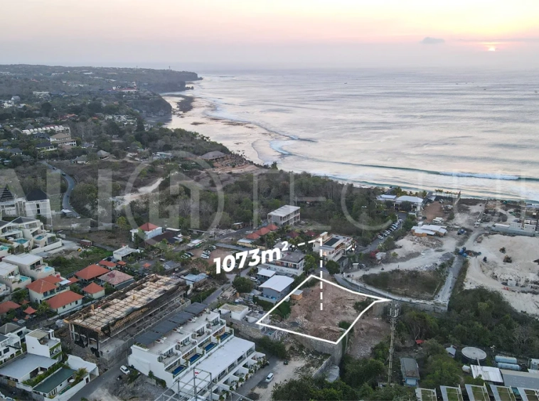 Aerial view of 1,073m² leasehold land for sale near Bingin Beach, Uluwatu, overlooking the ocean with stunning sunset views, surrounded by villas, cafés, restaurants, and coastal developments.