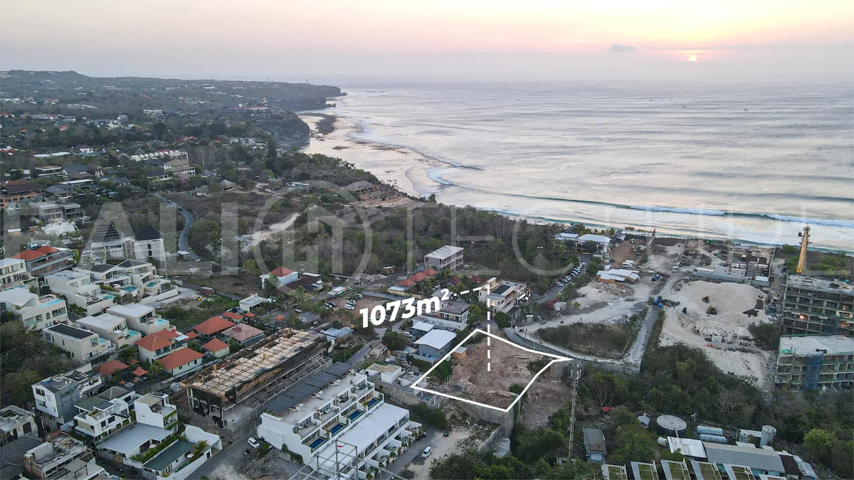 Aerial view of 1,073m² leasehold land for sale near Bingin Beach, Uluwatu, overlooking the ocean with stunning sunset views, surrounded by villas, cafés, restaurants, and coastal developments.