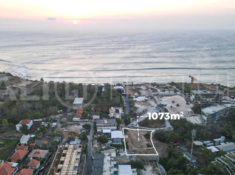 Aerial view of 1,073m² leasehold land for sale near Bingin Beach, Uluwatu, overlooking the ocean with stunning sunset views, surrounded by villas, cafés, restaurants, and coastal developments.
